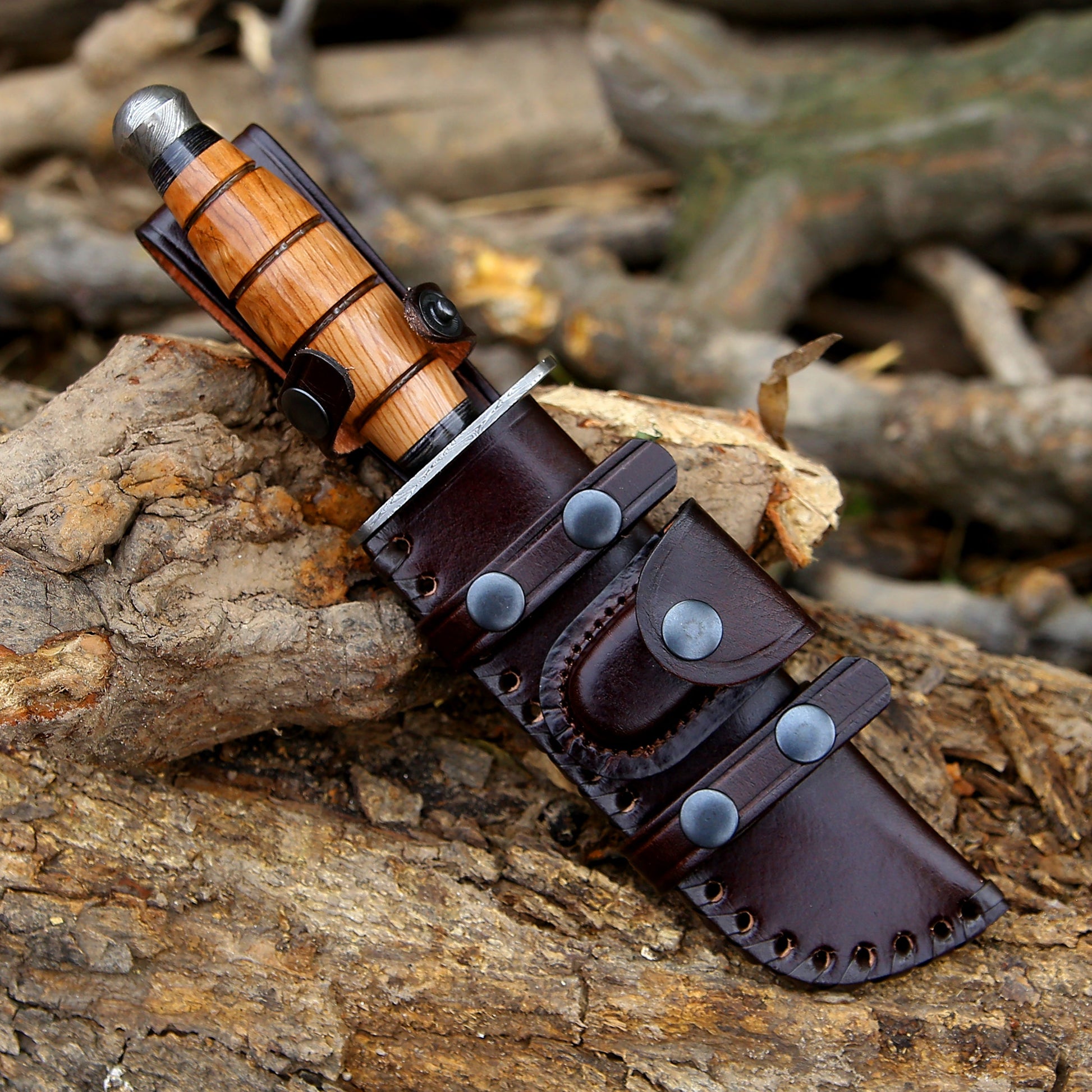Wooden-handled knife with leather sheath on a wooden surface