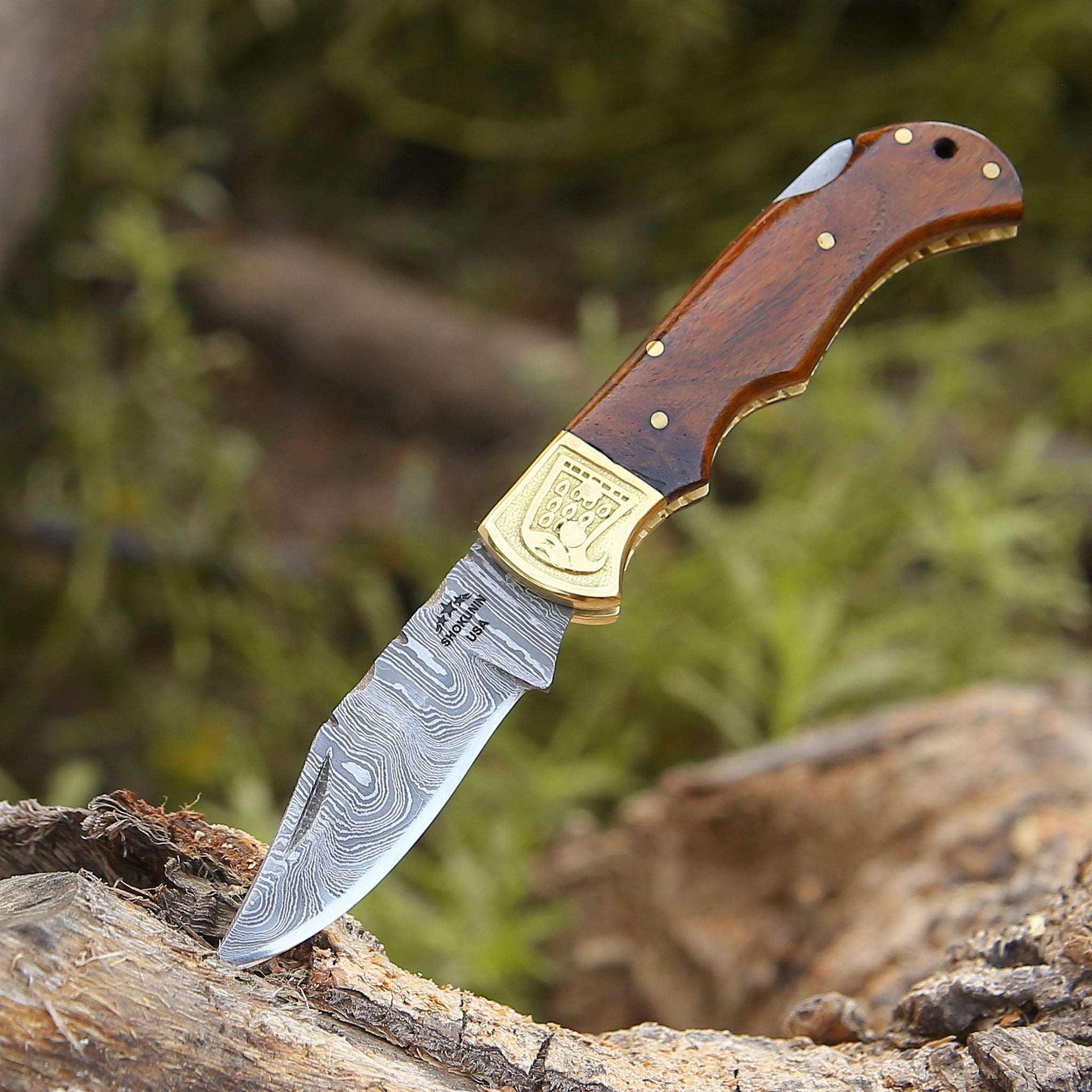 Knife with wooden handle and gold emblem on a natural background